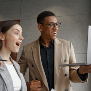 Duas pessoas surpresas olhando para a tela do notebook