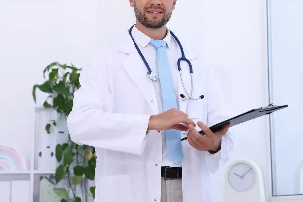 homem sorridente com trajes de médico e prancheta